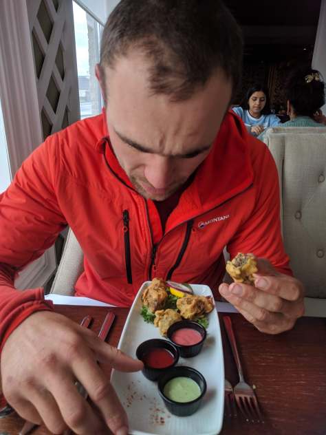 A picture of Jesse sitting in an Indian restaurant, eating haggis pakora's with his fingers.