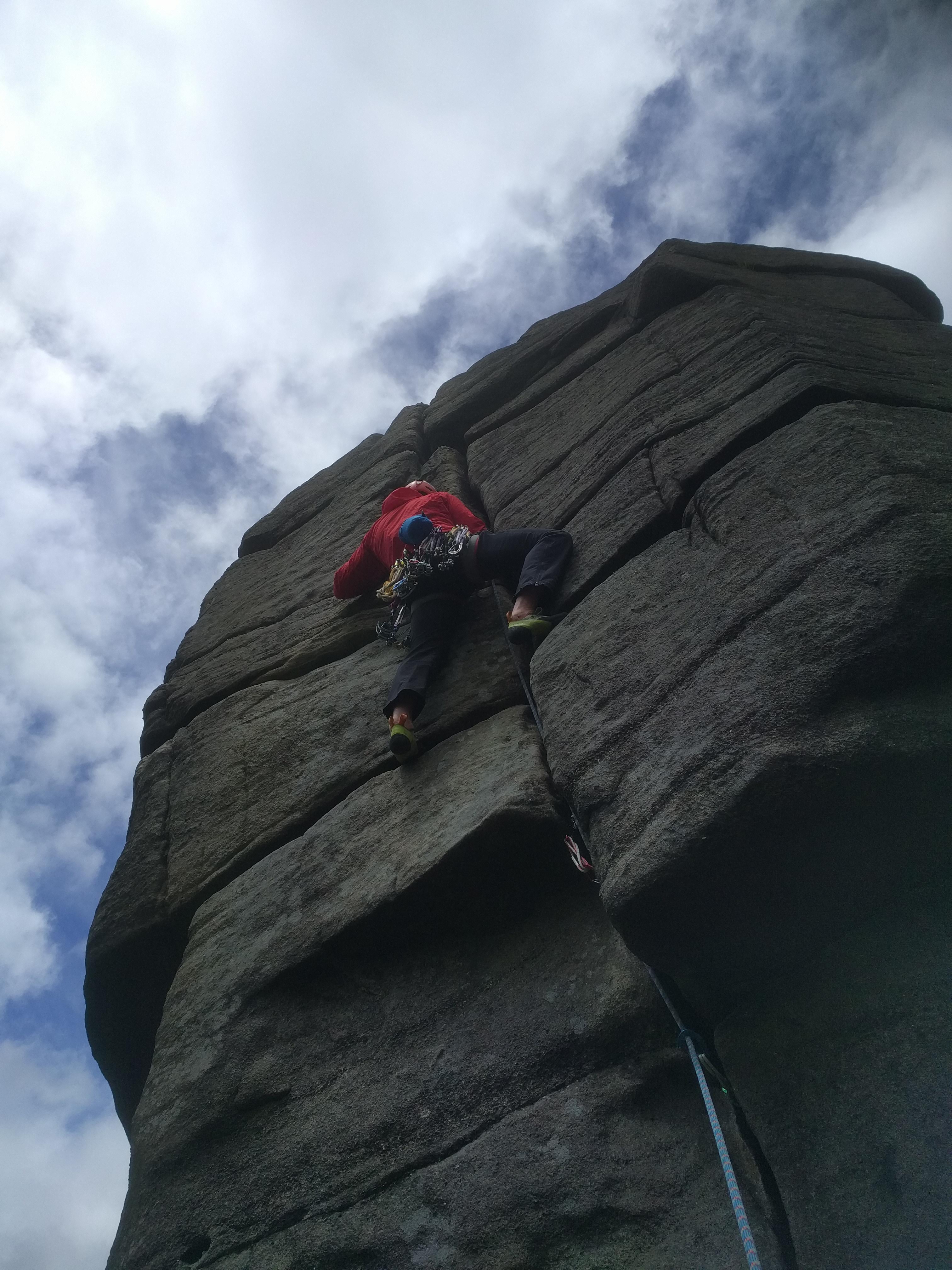 A picture of Jesse, in his windproof red jacket climbing The File at Higgar Tor