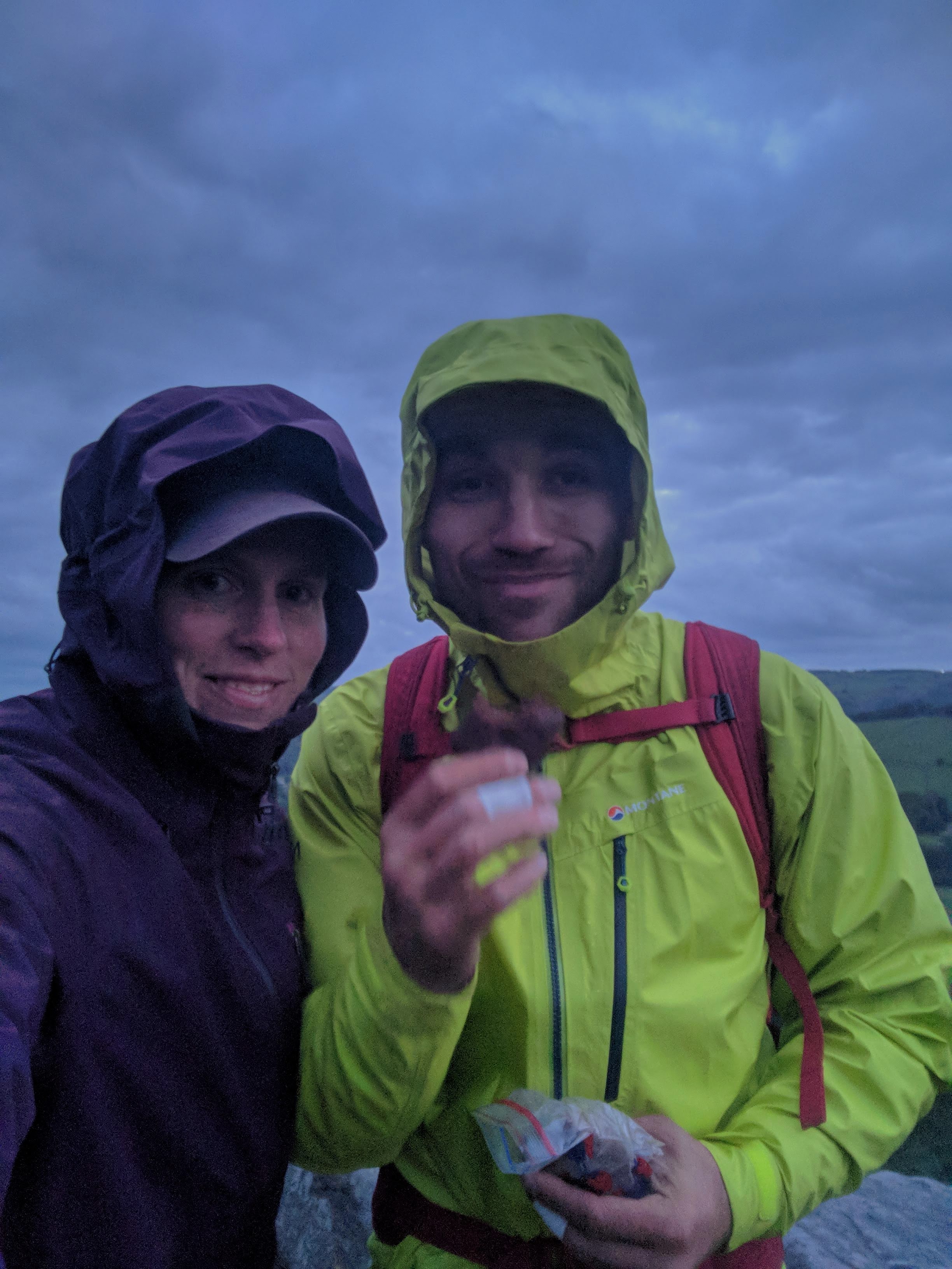 A picture of Molly and Jesse with their waterproof jackets on with hoods up, looking very tired, as it starts to get dark.