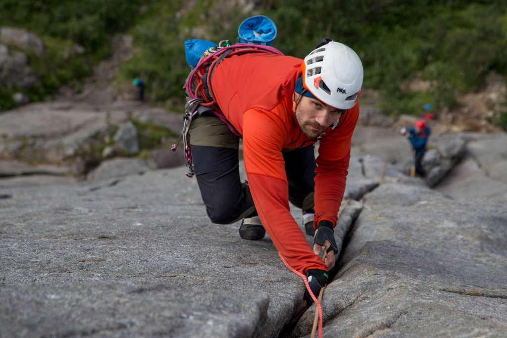 A photo of Jesse climbing a hand crack, wearing crack gloves.