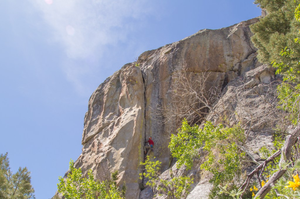 A photo showing Jesse half way up the final corner of Beef Jello, a super classic jamming route in the city of rocks.
