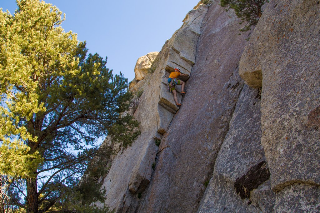 A photo of Jesse climbing a 3 stepped corner in the shade.