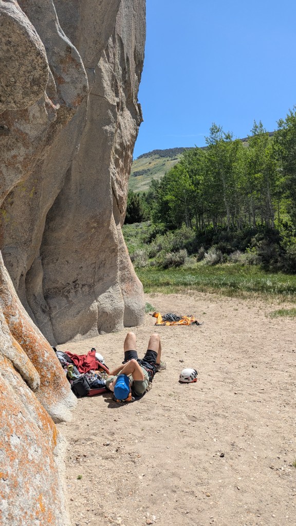 A photo of Jesse lying on his back basking in the sunshine below Double Cracks.