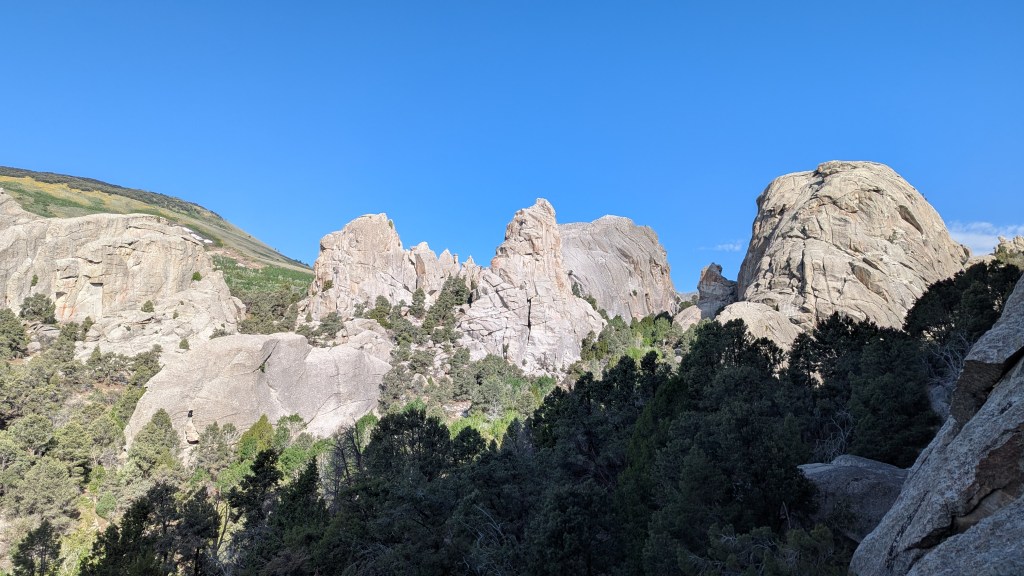 A photo showing the landscape of the city of rocks national park. With huge tower rock towers set in a a vista of pine trees and clear blue skies.